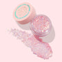 Moonlight Legend ColourPop Glitter Gel spreads from an open clear jar, showcasing iridescent pink and opal chunky glitter flakes; pale pink lid with celestial graphic sits beside on a soft pink backdrop, ideal for face and body sparkle.