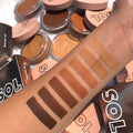 Forearm shows swatches of ColourPop SOL Face & Body Bronzing Balm, highlighting the Deep shade as a rich espresso stripe, blended alongside lighter tones, with open SOL Body balm compacts and peach lids scattered in the background.