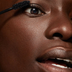 ColourPop Act Natural Mascara in Black brushing through upper eyelashes with a tapered bristle wand, close-up on a modelβs eye for defined, natural-looking length and lift.