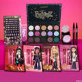 Bratz x ColourPop Full Collection set displaying a multi-pan eyeshadow palette with jewel-toned mattes and shimmers, face gems, two iridescent glitter gels, two liquid liners, and four character lip kits on a hot pink backdrop; ColourPop Full Collection Set.