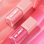 Two ColourPop So Juicy Lip Oil bottles from the It's Giving Juicy bundle lie diagonally, showing rosy-pink shades in clear square tubes with blush caps and SO JUICY plumping glossy lip oil text on a glossy pink backdrop; ColourPop So Juicy Lip Oil Set.