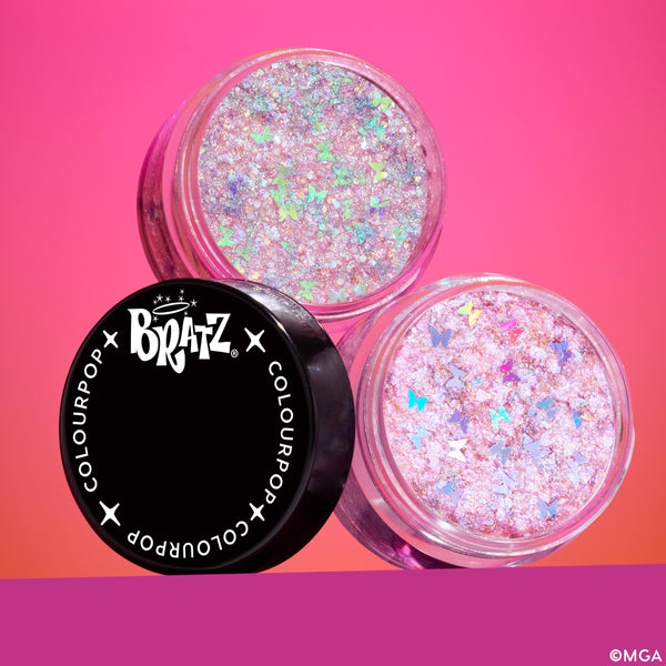 Bratz x ColourPop Full Collection glitter gel pots display two open jars of iridescent pink flakes with butterfly-shaped confetti beside a black Bratz x ColourPop lid, sparkling on a pink gradient background, part of the ColourPop Full Collection Set.