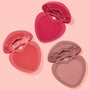 ColourPop Totally Lovestruck Heart Powder Blush Set displaying three open heart-shaped pressed powders in lip-shaped compacts - vivid fuchsia, warm coral, and soft nude pink - arranged diagonally on a pastel pink backdrop.