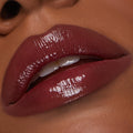 Glossy deep-berry lips wearing Juicy Berry, the ColourPop So Juicy Plumping Lip Liner & Balm Set defining the lip line while the balm delivers high-shine, plumped finish; close-up of a slightly parted mouth with teeth visible.