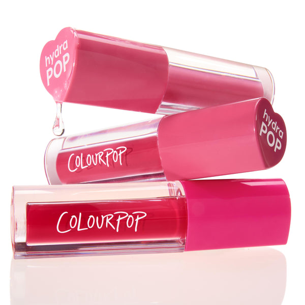 Tickle Me Pink ColourPop Lip Stain tubes stacked and gently dripping, showing vibrant rosy pink shades in clear barrels with hot pink caps stamped “hydra POP” and the ColourPop logo, styled on a bright white studio background.