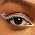 Graphic metallic silver eyeliner defines a close-up eye, with ColourPop Crème Gel Liner in Total Essentials tracing the upper lash line and inner corner and forming a sharp outer wing, shown on smooth warm-toned skin for a bold, precise look.