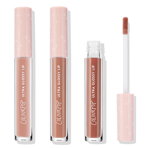 Three ColourPop Ultra Glossy Lip tubes in Cool Nudes stand upright, one opened with a doe-foot applicator, showing cool-toned nude gloss; clear barrels and blush pink star-printed caps on a white background, three-piece nude lip gloss bundle.