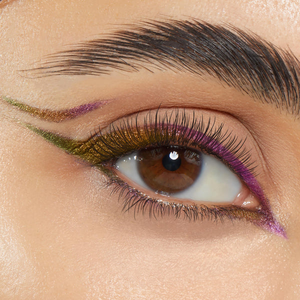 Good Shift ColourPop Crème Gel Liner tracing a graphic double wing on a brown eye, shifting olive green to violet along the upper and lower lashlines, showcasing smooth, metallic payoff on a neutral lid under a groomed brow.