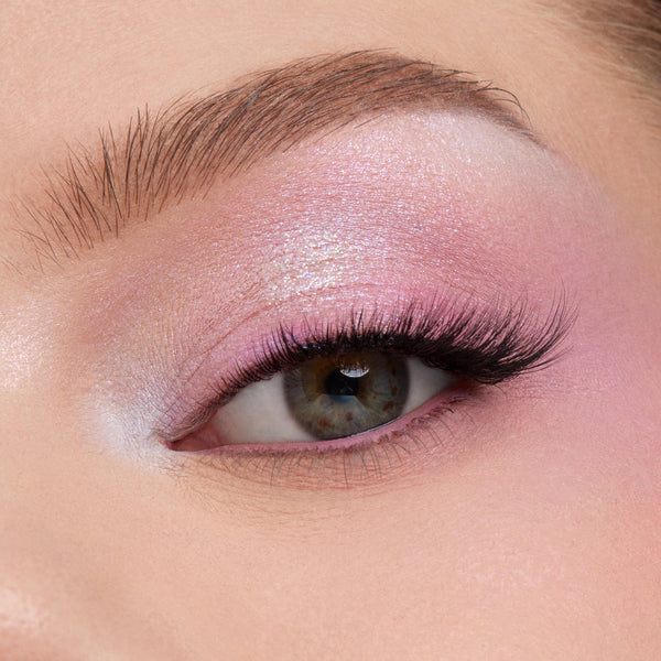 Shimmering pastel pink‑lilac eyeshadow blends across a close-up eyelid with fluttery lashes, showcasing the color payoff of the In A Trance shadow palette, a ColourPop Shadow Palette, perfect for soft, iridescent looks.