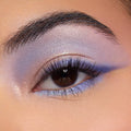 Shimmery lavender-to-blue winged eyeshadow accenting a brown eye, with an iridescent inner corner and lilac lower lash line, showcasing shades from the Disney Lilo and Stitch Collection ColourPop Full Collection Set in a close-up beauty shot.