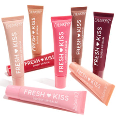 Eight ColourPop Fresh Kiss Glossy Lip Balm tubes fan out on white, some upright and one laid across, displaying nude, pink, coral, red, brown, and berry shades; Gloss Goals Full Collection Set, a ColourPop Full Collection Set for shiny, hydrated lips.
