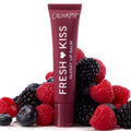 ColourPop Fresh Kiss Glossy Lip Balm tube stands upright amid raspberries, blackberries, and blueberries on a white backdrop, representing the Get Rich ColourPop Glossy Lip Balm Trio with a deep berry-colored tube and high-shine finish.