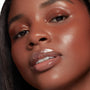 Glossy, plumped lips catch the light, showcasing Double The Juiciness from the ColourPop So Juicy Plumping Glossy Lip Oil & Lip Liner Kit; dewy skin and copper shimmer eyeshadow frame the close-up, highlighting a high-shine, cushiony finish.
