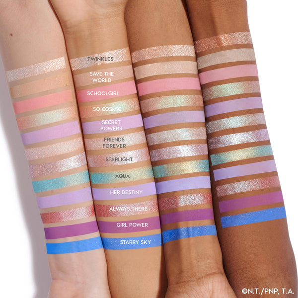 Swatched eyeshadows on three forearms display the ColourPop Prettiest in the Cosmos shadow palette set, 12 matte and shimmer shades from soft pinks, lilacs, and golds to vivid blue; labels show Twinkles, So Cosmic, Starlight, Aqua, Starry Sky.