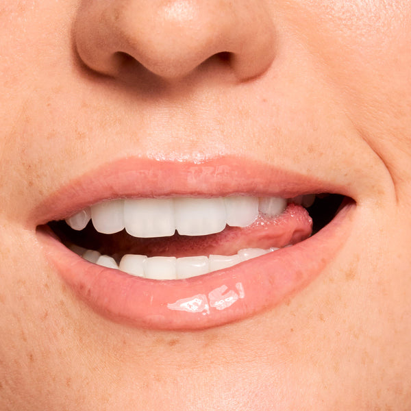 Glossy lips smile, wearing a sheer peachy-pink balm that showcases shine and smoothing from Gloss Goals Full Collection Set; extreme close-up swatch in studio lighting, ideal for shoppers searching ColourPop Full Collection Set.