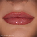 Glossy lips wearing ColourPop So Juicy Plumping Gloss Stick in Pinky Who, delivering sheer rosy pink shine that visibly plumps and smooths the mouth, shown in a tight close-up on natural skin as a beauty swatch.
