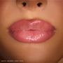 Close-up lips wearing ColourPop So Juicy Plumping Gloss Stick, shade Pinky Who, showing a cushy, plumped look with sheer medium‑pink, high‑shine finish under studio lighting.