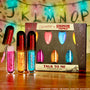 Stranger Things x ColourPop Full Collection set showcasing the Talk To Me ColourPop Ultra Glossy Lip trio - pink, gold, and blue tubes, one with wand open - on a wood table before the branded box and alphabet string-lights backdrop.