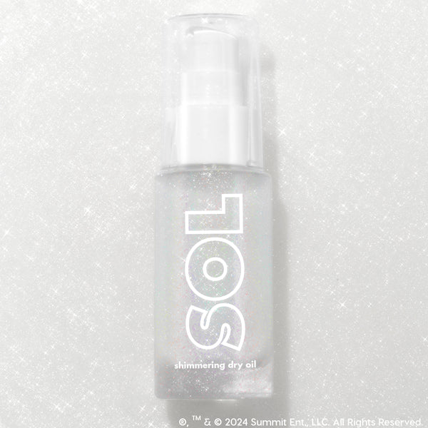 Like Diamonds pump bottle displaying iridescent micro-shimmer through frosted glass with bold white SOL logo, ColourPop SOL Shimmering Dry Oil, standing upright on a silver glitter backdrop that enhances the sparkle for a luminous body glow.