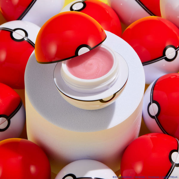 Type Advantage ColourPop Lip Set lip mask opens to reveal shimmery pink balm in a Poké Ball–inspired jar, displayed on a white pedestal and encircled by glossy red-and-white spheres.
