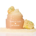 Vanilla Cake ColourPop Lip Scrub jar sits open, sugary scrub mounded on top and swatched at the base, flanked by funfetti cake crumbs on a clean white studio background.