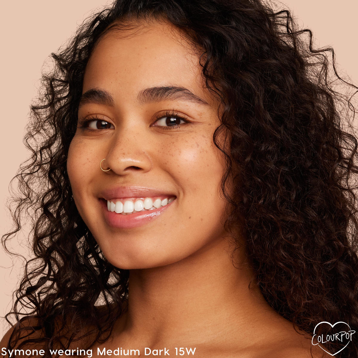Model smiling in a close-up, wearing ColourPop Pretty Fresh Tinted Moisturizer in Medium Dark 15 W, showing dewy, even coverage and natural finish against a soft beige background.