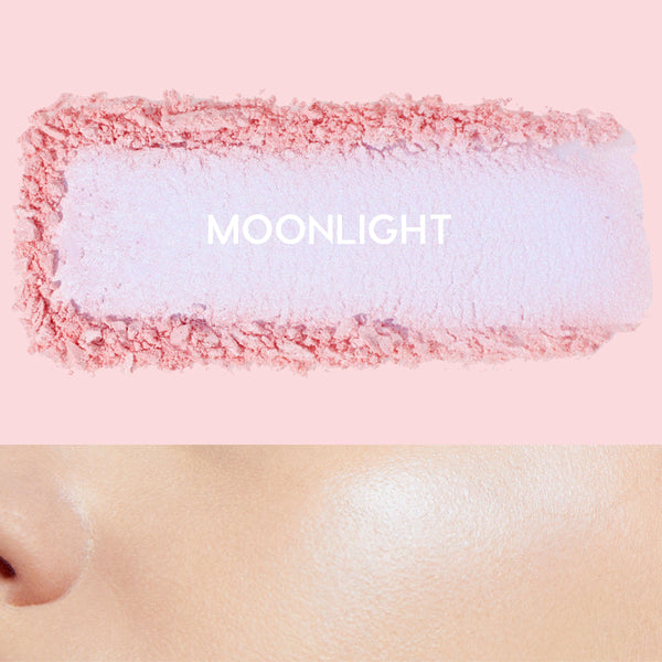 Moonlight ColourPop Pressed Powder Highlighter swatch spreads icy lavender with pink edges, while a nearby cheek glows with its pearly sheen, set on a pastel pink background to show color payoff and luminous finish.