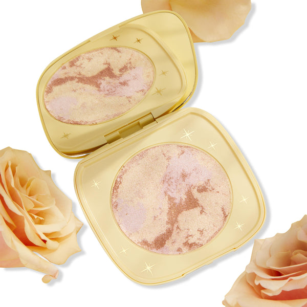 Special Guest ColourPop Super Shock Highlighter opens in a pale yellow compact, revealing a marbled champagne, rose-gold, and soft pink pan with tiny star accents, set on a white backdrop with peach roses for a luminous, buildable glow.