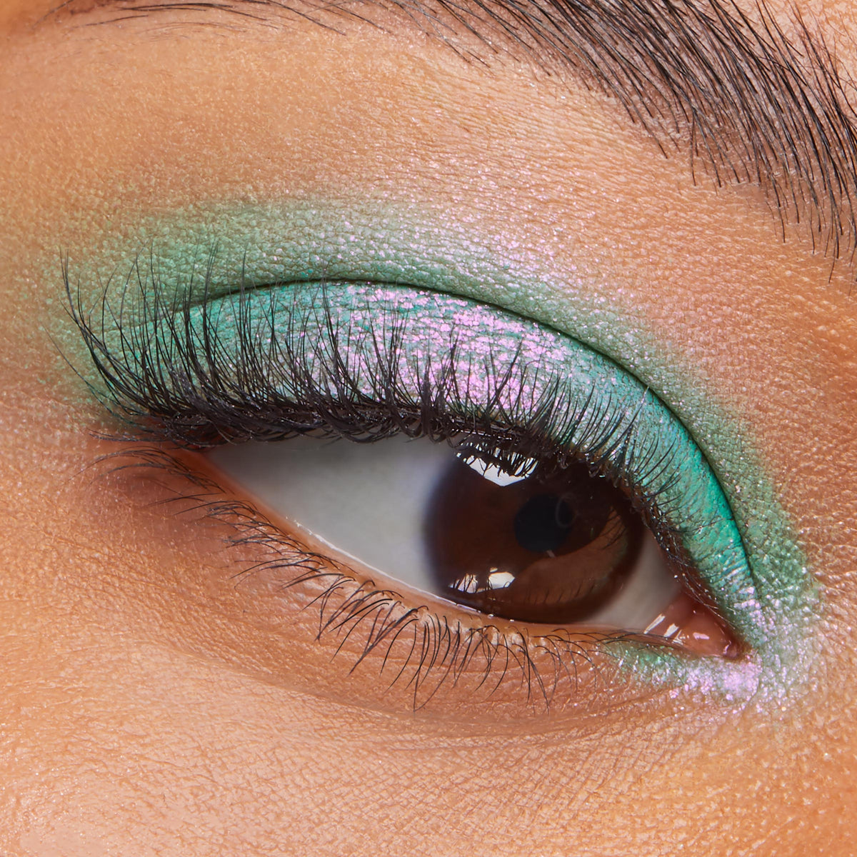 Solar Beam ColourPop Super Shock Shadow gleams on the eyelid, shifting mint green to pink-lilac, while lashes frame the close-up eye; creamy, blendable metallic finish extends from lid to inner corner for vibrant color payoff.