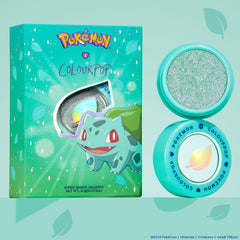 ColourPop Super Shock Shadow Solar Beam glimmers with mint-green and pink iridescent sparkle in an aqua pot, shown open beside its Pokemon x ColourPop Bulbasaur box on a teal backdrop, highlighting the leaf logo and collectible packaging.
