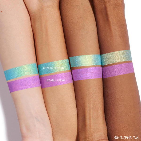 Crystal Tokyo ColourPop Crème Gel Liner swatched in thick bands on four forearms, showing a duochrome aqua-to-gold shimmer above a lavender Azabu-Juban stripe, demonstrating payoff across light to deep skin tones on a white background.