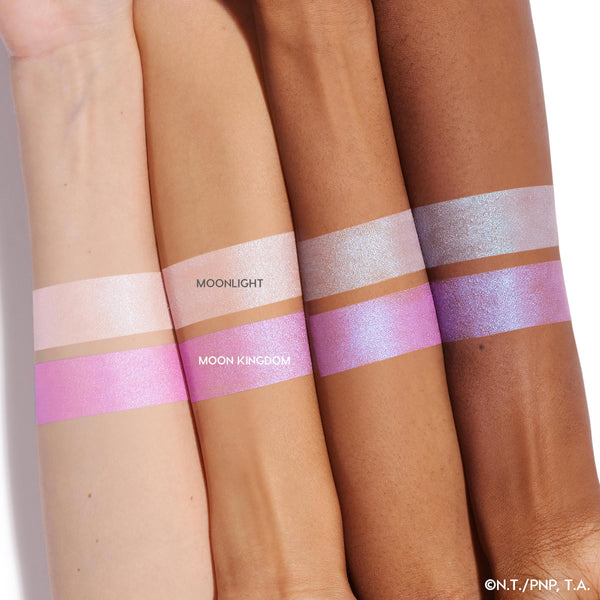 Moon Kingdom ColourPop Pressed Powder Highlighter swatched in bold bands on four arm skin tones, showing an iridescent pink-lavender glow with blue shift beneath the lighter Moonlight strip to compare payoff and shimmer across tones.