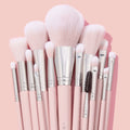 Smoke 'N Roses Brush Roll, a ColourPop Makeup Brush Kit, arranged upright with fluffy pink-and-white bristles and blush pink handles with silver ferrules, featuring powder, blush, shader, and spoolie brushes against a soft pink backdrop.
