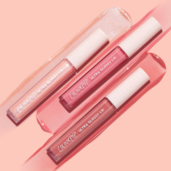 Tickled Pink ColourPop Ultra Glossy Lip trio, three pink glosses - shimmering pearl, bright rose, and soft mauve - in clear tubes with white caps, arranged diagonally on glossy swatches over a peach‑pink background.