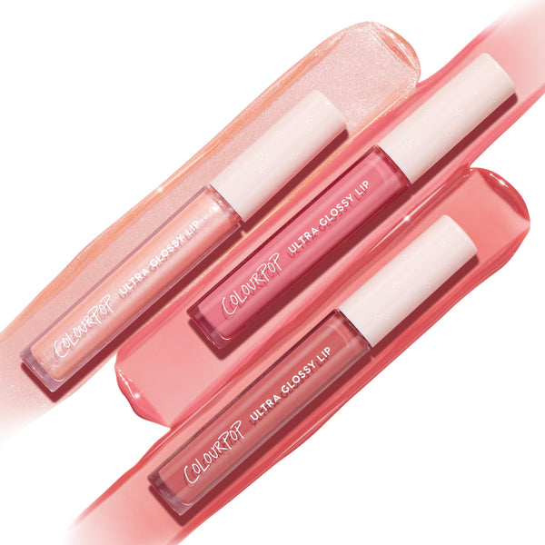 Tickled Pink ColourPop Ultra Glossy Lip trio resting on wide swipes of gloss - shimmery peach, rosy pink, and warm pink - tubes with white star caps angled diagonally, showcasing a high-shine finish on a clean white background.