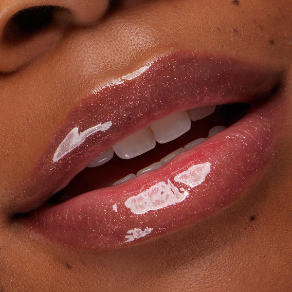 Shimmering pink gloss coats full lips, catching light in a high-shine, sparkly finish in a tight close-up, showcasing the Type Advantage ColourPop Lip Set for a hydrated, plump look against warm skin.