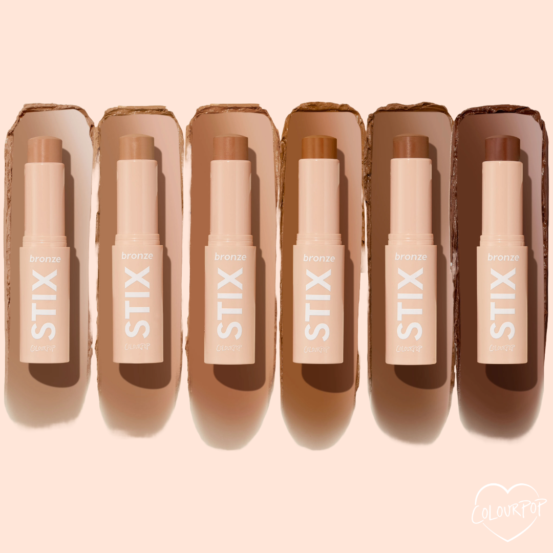 ColourPop Bronzer Stix in Laguna Beach shown upright and uncapped in a lineup of six bronze shades, each stick with a matching swipe behind it on a soft peach background, highlighting the creamy twist-up bronzer packaging.