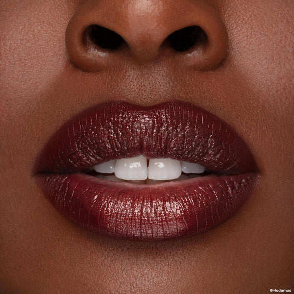 Glossy deep burgundy lips wearing ColourPop Cloe Lippie Kit, shown in close-up on deep brown skin; full-coverage lipstick with subtle sheen and a crisp lip line for a bold, vampy finish.