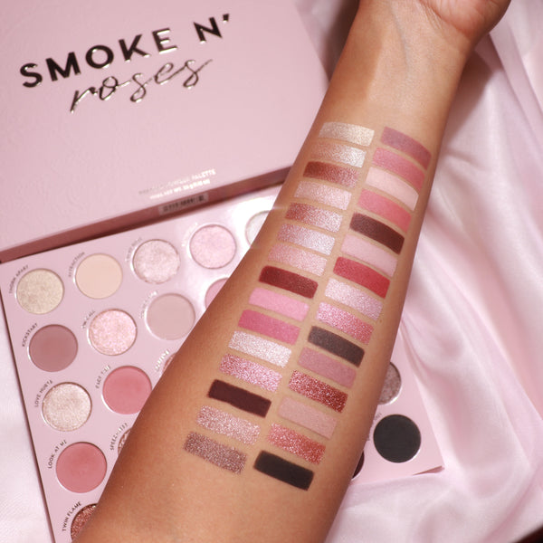 Total Smokeshow ColourPop Shadow Palette & Brush Set swatched on a forearm, showcasing rosy pinks, mauves, champagnes, and deep browns in matte and shimmer finishes beside an open pink palette on silky fabric.