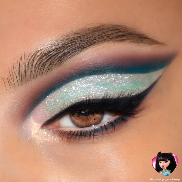Brown eye wearing iridescent mint‑lilac cut‑crease glitter, bold teal wing, and black liner, showcasing the Bratz x ColourPop Full Collection Set for a Jade‑inspired look; ColourPop Full Collection Set.