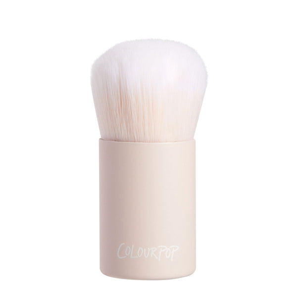 Mini Kabuki Face Brush with dense white bristles and a matte beige short handle branded ColourPop stands upright, ready to buff and blend foundation or powder; compact ColourPop Makeup Brush on a clean white background.