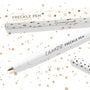 Soft Brown ColourPop Freckle Pen uncapped, felt-tip applicator ready to dot natural-looking freckles, shown with polka-dot cap and matching box on a white background speckled with brown spots; 1.0 ml makeup pen for faux freckles.