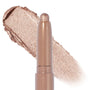ColourPop Shadow Stix in Socialite glides on as a creamy, twist-up eyeshadow stick, depositing a metallic champagne-nude shimmer; product tip shown with a wide swatch of the pearly formula on a white background.
