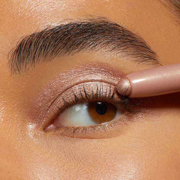 ColourPop Shadow Stix Socialite glides over the eyelid, applying shimmery rose‑champagne cream shadow in a tight close-up, showcasing metallic payoff and precise, easy application with the twist-up stick.
