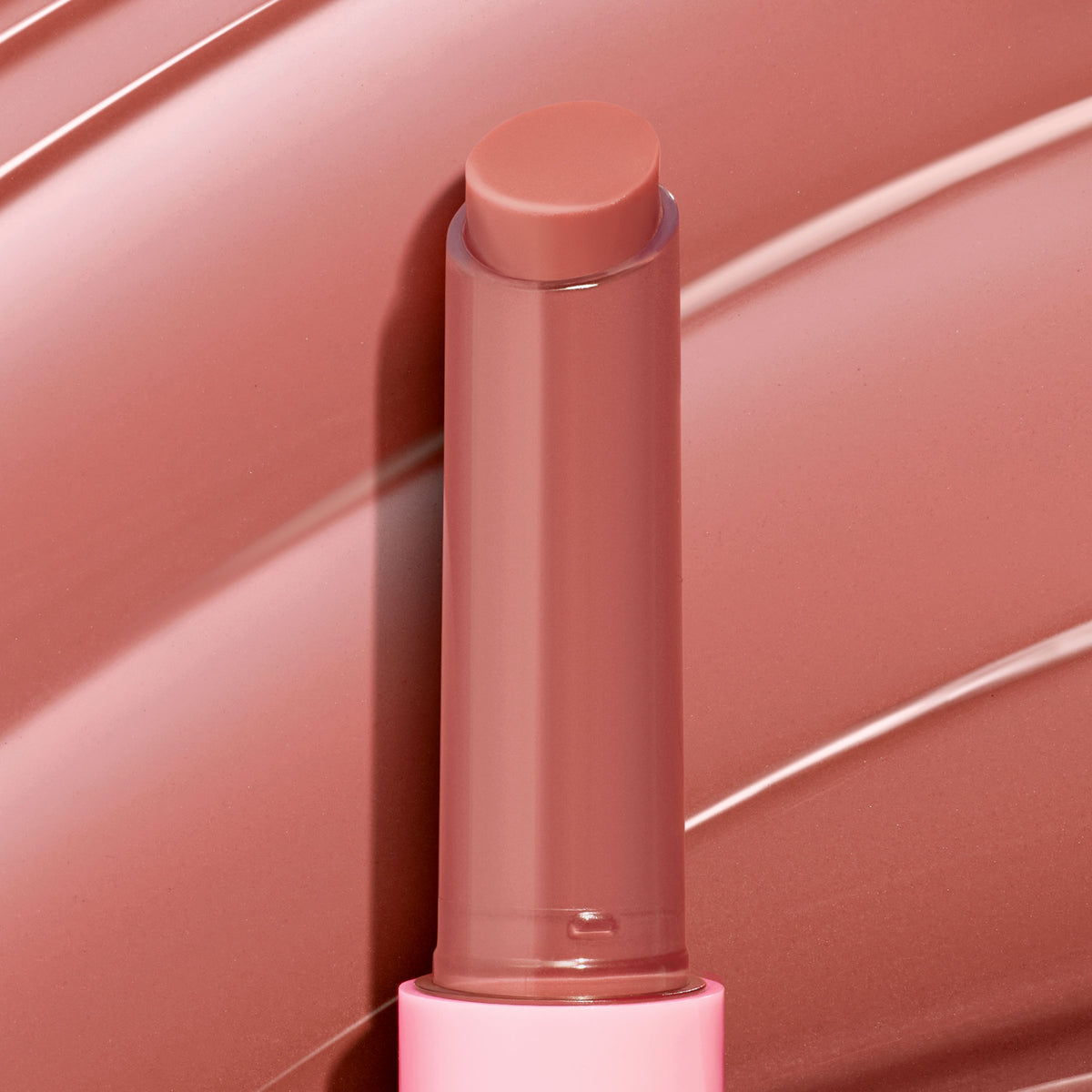 ColourPop So Juicy Plumping Gloss Balm with Peptides in Vacay Mode stands uncapped with the bullet extended, a warm rosy nude shade, in a pink tube against a matching glossy swatch background.