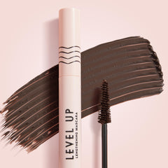 ColourPop Level Up Brown lengthening mascara, tube and tapered spoolie sweeping a rich brown swatch across a soft pink background, showcasing the deep pigment and brush detail for this Brown shade.