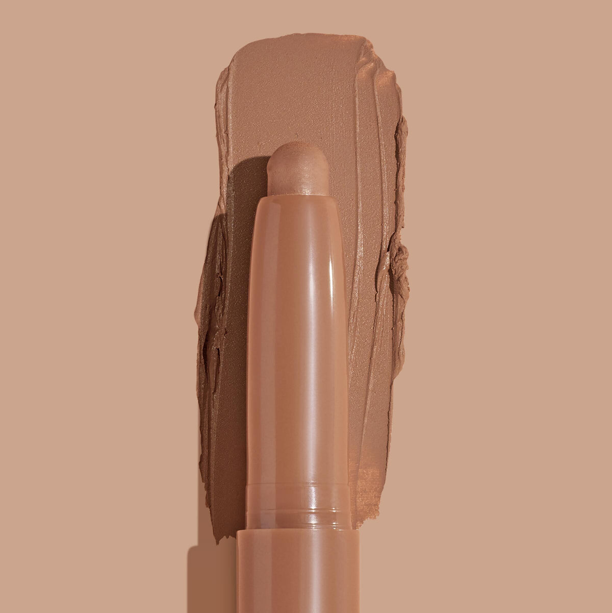 ColourPop Shadow Stix in Cocktail Party showcasing the creamy stick tip against a wide swipe of warm matte tan pigment, highlighting smooth payoff and portable eyeshadow stick on a matching nude background.