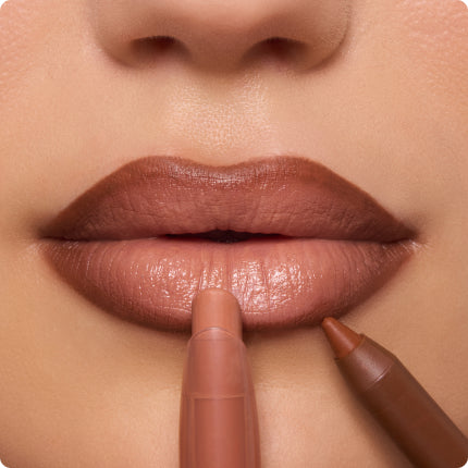 Full lips apply Colourpop nude lip color with a creamy lipstick crayon while a brown lip liner defines the cupid’s bow, close-up beauty shot showing a glossy, warm beige-brown finish against smooth skin.