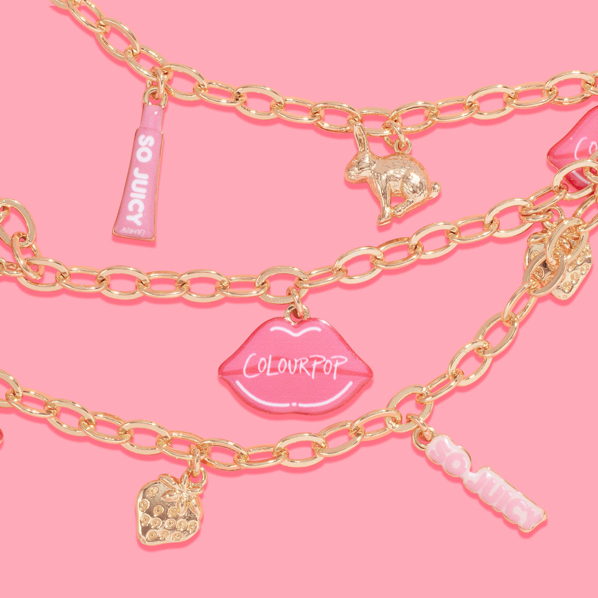 Brooklyn Charm x ColourPop Necklace showcasing gold link chains with playful charms - pink lips reading “ColourPop,” pink “So Juicy” tube tags, a gold bunny, and a jeweled strawberry - layered on a bright pink background.