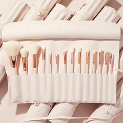 Ultimate Brush Roll displaying a full set of soft white-bristle makeup brushes with rose-gold ferrules neatly slotted in a blush pink travel roll, set on matching rolled cases - ColourPop Makeup Brush Kit for face and eye application.